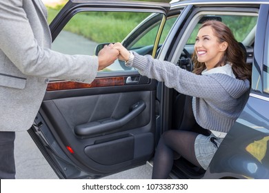 Handsome Man Holding Car Door For Beautiful Businesswoman Daytime