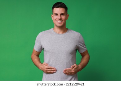 Handsome Man Holding Hands Near Stomach On Green Background