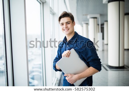 Handsome man holding a laptop in hall