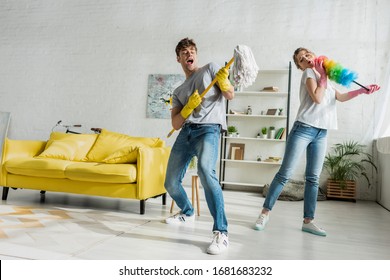 Handsome Man Holding Mop And Singing With Woman While Doing Spring Cleaning