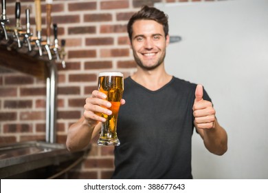 Handsome Man Holding A Pint Of Beer With Thumbs Up In A Pub