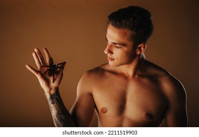 Handsome Man Holding Tarantula While Standing At The Studio