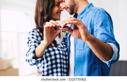 Handsome Man Is Hugging A Stunning Woman And They Both Are Holding A Key Feeling A Sheer Joy Due To Their House Moving.