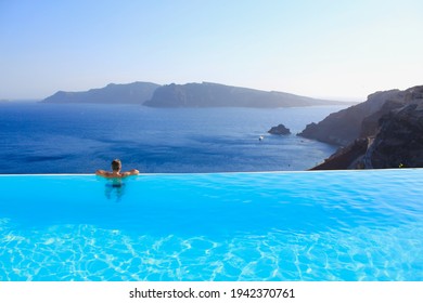 Handsome man in infinity pool, enjoying the panoramic view of mediterranean sea and volcanic mountains in background. Santorini, Greece. Concept for wanderlust, dreaming vacations, enjoy life. - Powered by Shutterstock