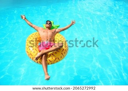 Handsome man with inflatable ring in swimming pool