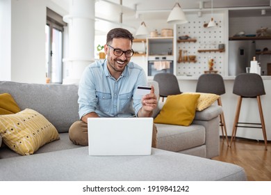 Handsome man with laptop and credit card at home, portrait. Shot of a handsome young businessman using a computer while holding a credit card in an home office