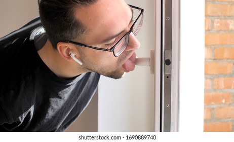 Handsome Man Licks A Doorknob. Covidiot. Coronavirus Or COVID-19. 