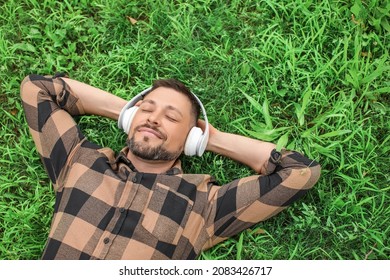 Handsome man listening to music while relaxing in park