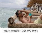 Handsome man lying down on suspended enjoying a cocktail 