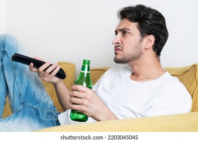 Handsome Man Lying On The Couch And Watching Tv And Drinking Beer	