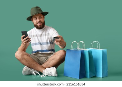 Handsome Man With Mobile Phone And Gift Card On Green Background. Black Friday Sale