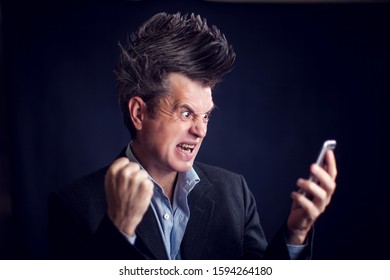 Handsome Man With Mohawk Wearing Suit Using Mobile Phone In Front Of Black Background.