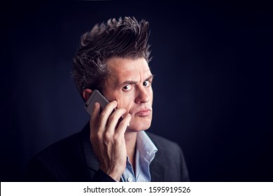 Handsome Man With Mohawk Wearing Suit Using Mobile Phone In Front Of Black Background.