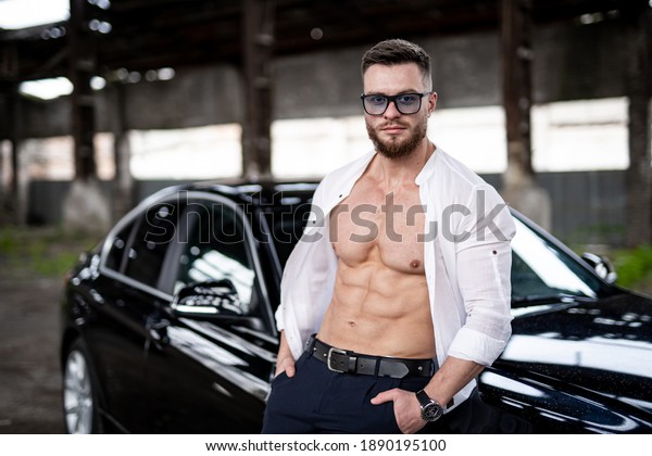 Handsome man near the car. Luxury life. Rich man\
in white unbuttoned\
shirt.
