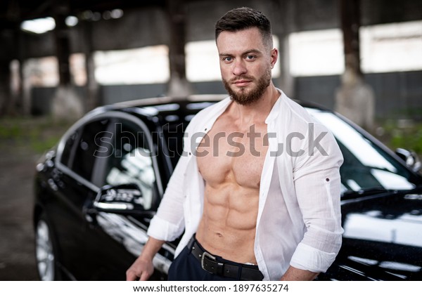 Handsome man near\
the car. Luxury life. Rich man in white unbuttoned shirt. Fashion\
model male. Conceptual\
photo.
