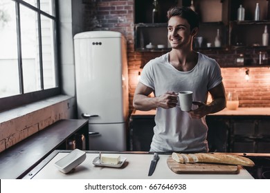 Handsome man on kitchen is smiling and drinking coffee in the morning. - Powered by Shutterstock