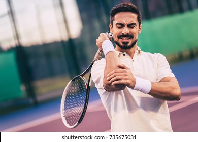 Handsome Man On Tennis Court. Young Tennis Player. Pain In The Elbow