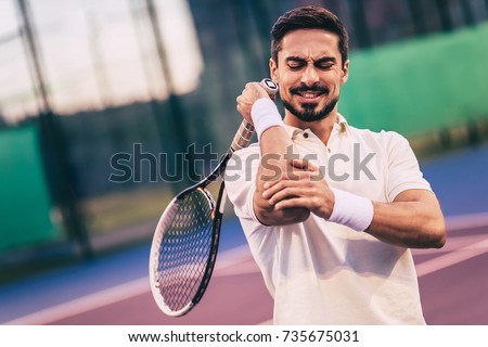 Handsome man on tennis court. Young tennis player. Pain in the elbow