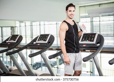 Handsome Man On Treadmill Drinking Water At The Gym