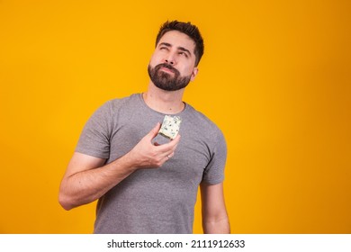 Handsome man with piece of cheese on yellow background. Boy with a slice of cheese in his hand