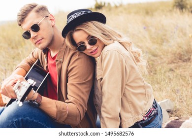 handsome man playing acoustic guitar and attractive woman hugging him 