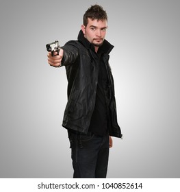 handsome man pointing with gun against a grey background