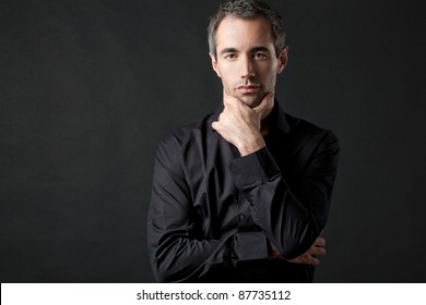 Handsome Man Posing In Black Shirt On Dark Background In Studio.