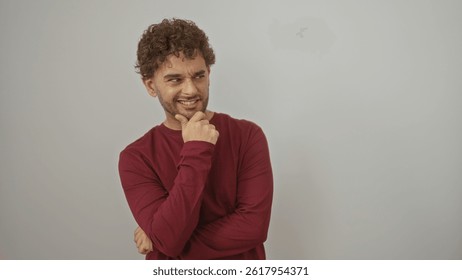 Handsome man posing over isolated white background wearing red sweater smiling thoughtfully with hand on chin.