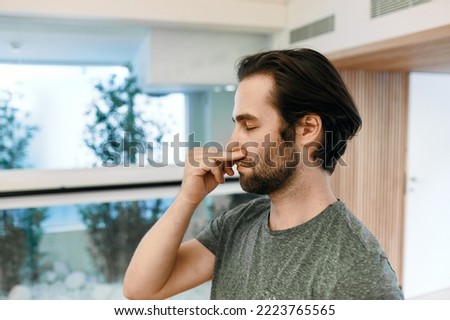 Handsome man practicing yogic breathing technique, pranayama technique and alternating right and left nostril breathing. Yoga breathing exercises