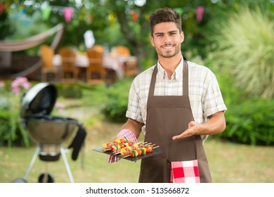 Handsome man preparing barbecue for friends, France