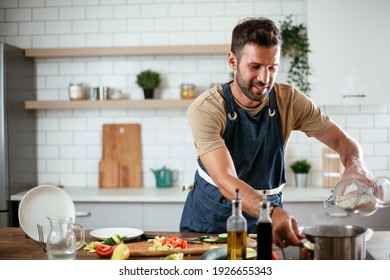 Handsome Man Preparing Pasta In The Kitchen. Guy Cooking A Tasty Meal.