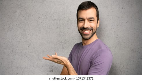 Handsome man presenting an idea while looking smiling towards over textured wall