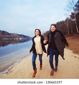 Handsome Man And Pretty Woman Having Fun On The Beach. Young Couple Running And Smiling In Spring