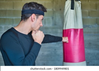 A Handsome Man Punching A Boxing Bag