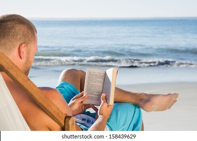 Handsome Man Reading A Book On The Beach