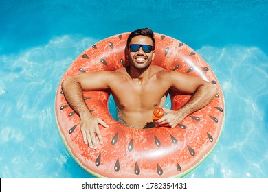 Handsome Man Relaxing Alone On A Float In The Pool On A Hot Summer Day