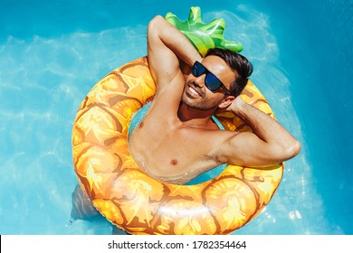 Handsome man relaxing alone on a float in the pool on a hot summer day