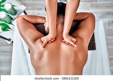 Handsome man relaxing and enjoying a deep tissue back massage at the spa salon. Top view