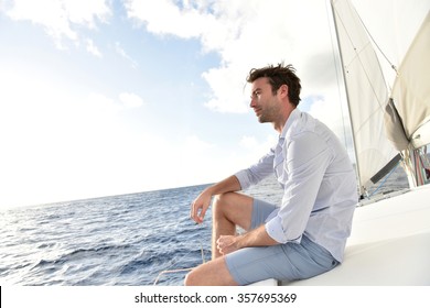 Handsome man relaxing on saiboat in middle of the sea