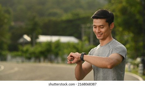 Handsome Man Resting And Checking His Heart Rate Data On Smartwatch During Morning Workout In The Park