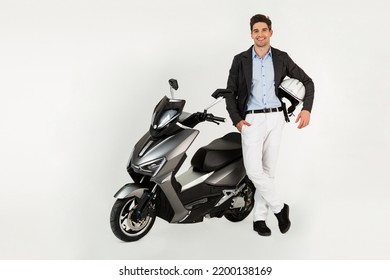 handsome man riding on electic motorbike scooter isolated on white studio background, standing attractive dressed in suit elegant young business hipster modern style