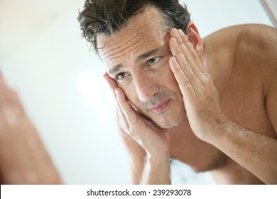 Handsome man rinsing face after shaving