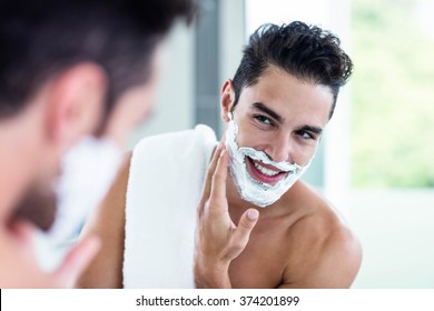Handsome man shaving his beard in bathroom