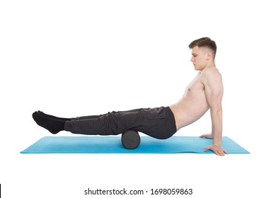 Handsome man shows exercises using a foam roller for a myofascial release massage of trigger points. Massage of the posterior thigh muscle. Isolated on white.