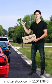 Handsome man with a sign hitch hiking to a concert