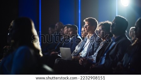 Handsome Man Sitting in a Crowded Audience at a Business Conference. Corporate Delegate Watching Inspirational Entrepreneurship Presentation About Developing Markets and Financial Opportunities.