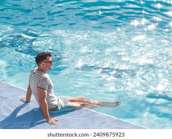 Handsome man sitting near the swimming pool of a cruise ship. Sunny morning, clear day. View from above. Closeup, outdoors. Vacation and travel concept - Powered by Shutterstock