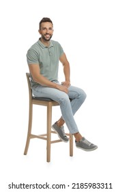 Handsome Man Sitting On Stool Against White Background