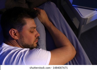 Handsome Man Sleeping On Pillow In Dark Room At Night, View From Above. Bedtime