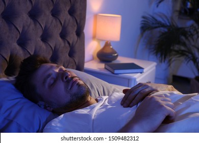 Handsome Man Sleeping On Pillow In Dark Room At Night. Bedtime